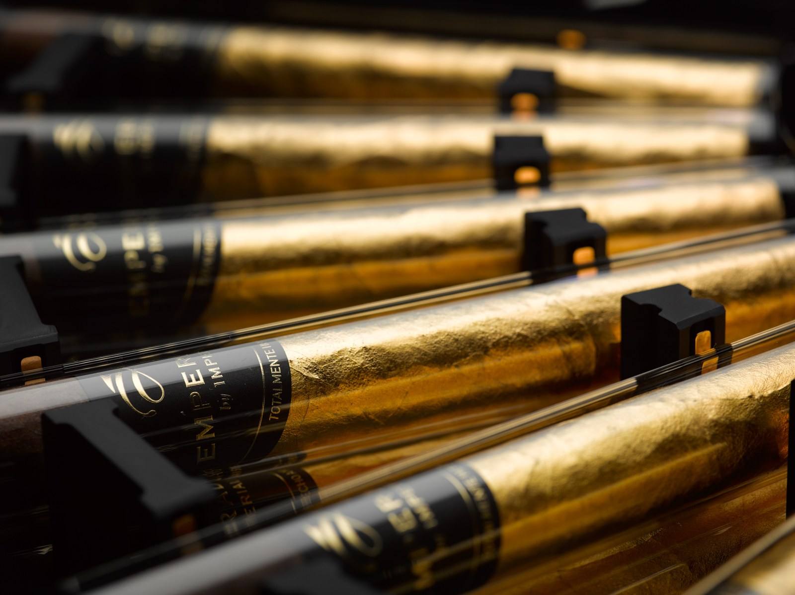 Cigars wrapped in gold leaf resting in glass tubes