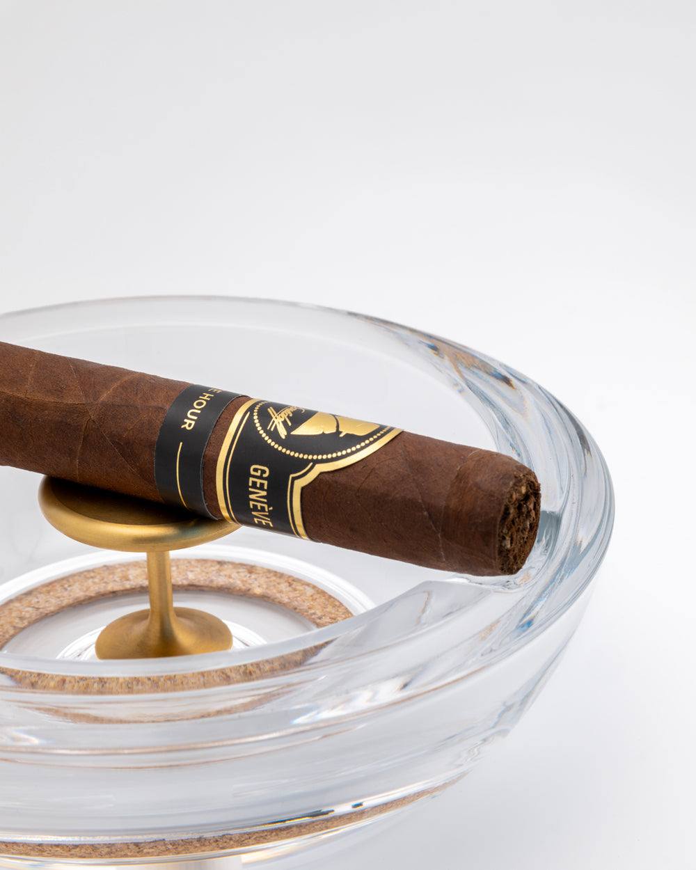 A cigar resting on a brass tapper inside the open crystal base of the Murmmr ashtray