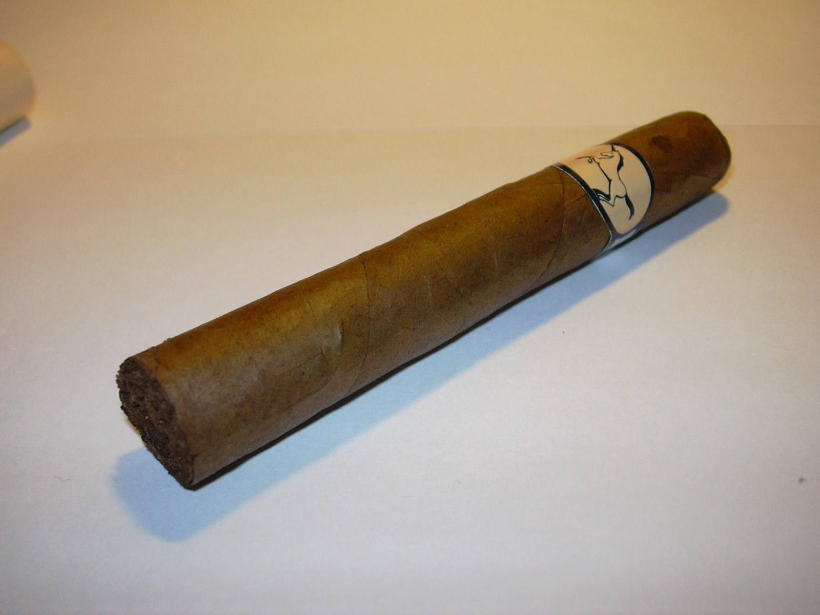 A figurado cigar on a dark wooden table. Representative photograph.
