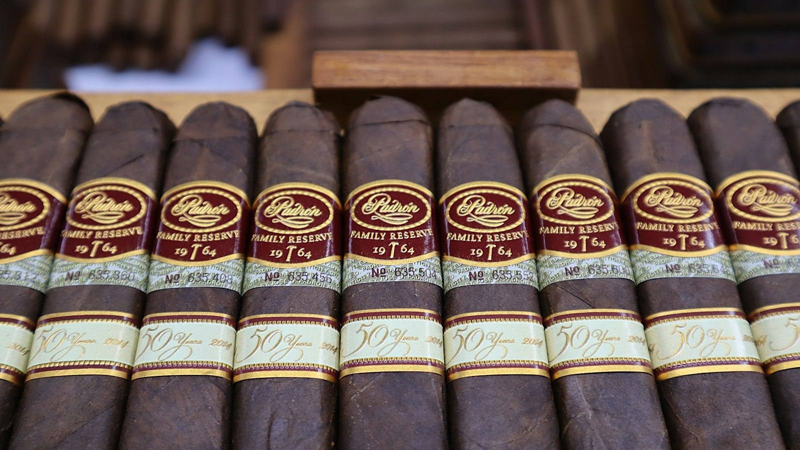 A row of Padron Family Reserve cigars showing their red and gold bands and numbered guarantee bands, photographed for Cigar Aficionado
