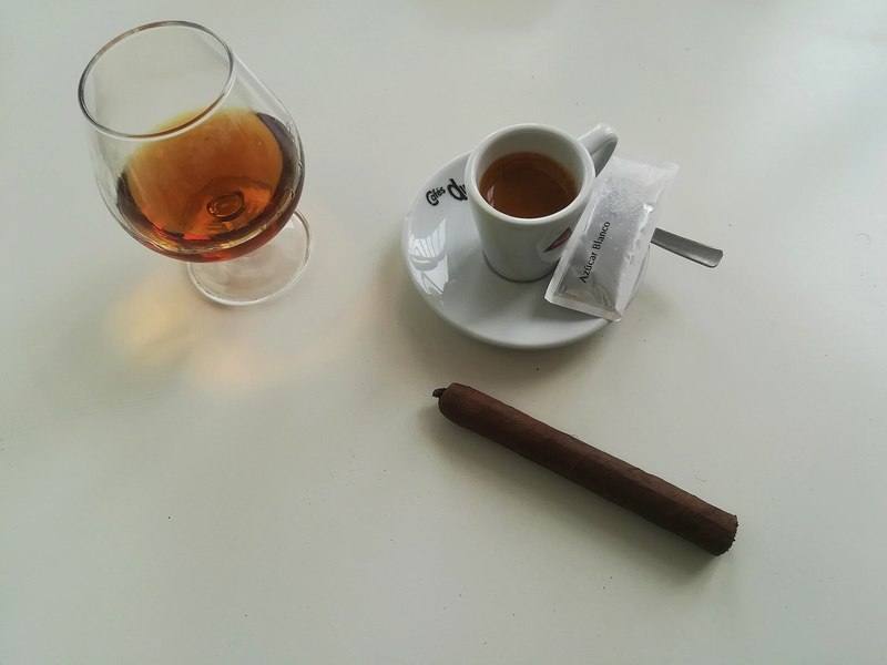 A cigar beside a cup of espresso and a glass of brandy