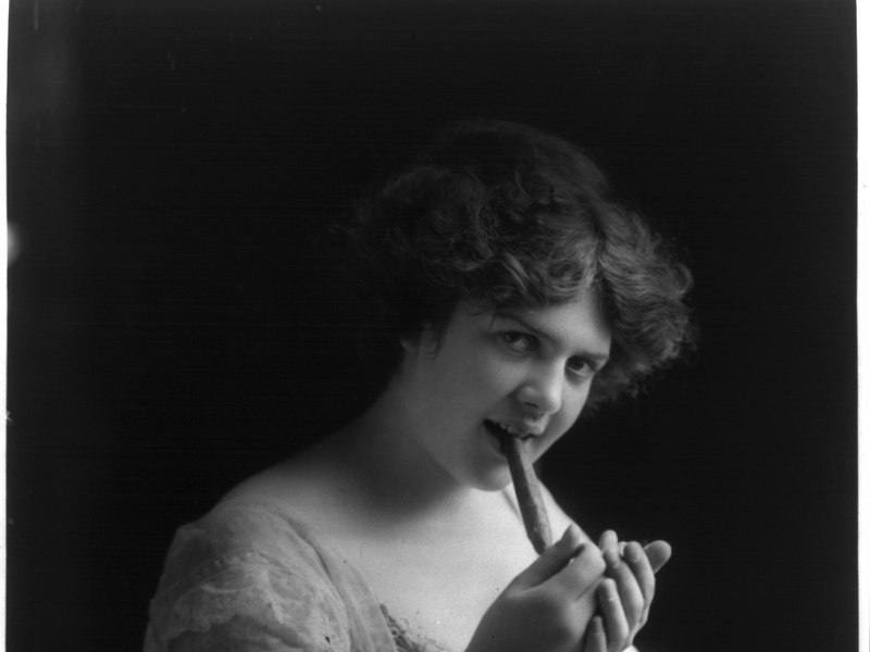 A young woman lighting a cigar